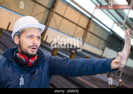 factory worker making gesture to stop with palm of hand Stock Photo
