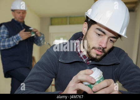 young worker in helmet having coffee break Stock Photo
