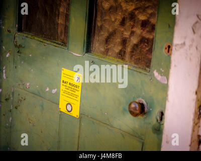 A bat roost warning sign attached to an old door warning visitors not to enter unless they are bat licence holders. Stock Photo