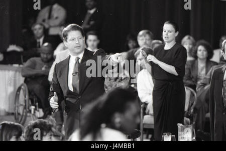 A man addresses an audience while a woman provides sign language interpretation behind him, ensuring accessibility during the presentation. Stock Photo