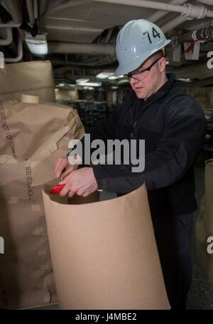 170223-N-TU932-020 BREMERTON, Washington (Feb. 23, 2017) Ship's Serviceman Seaman James Morra from Woodbridge, New Jersey, cuts protective material to cover a gear locker during painting aboard John C. Stennis (CVN 74). John C. Stennis is conducting a planned incremental availability (PIA) at Puget Sound Naval Shipyard and Intermediate Maintenance Facility, during which the ship is undergoing scheduled maintenance and upgrades. (U.S. Navy photo by Mass Communication Specialist 3rd Class Sierra D. Langdon / Released) Stock Photo