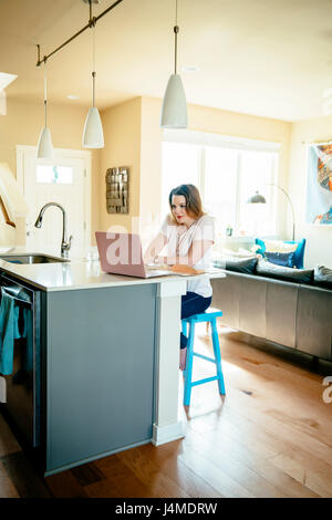 Woman sitting at counter using laptop Stock Photo