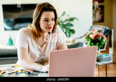 Woman sitting at table using laptop Stock Photo