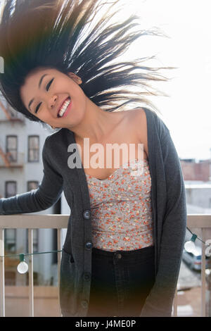 Mixed Race woman tossing hair on rooftop Stock Photo