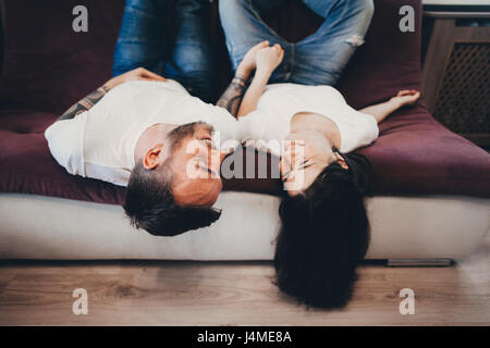 Caucasian couple laying upside-down on sofa Stock Photo