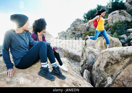 Women watching friend jumping on rock formation Stock Photo