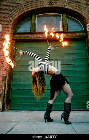 Caucasian woman juggling fire on city sidewalk Stock Photo