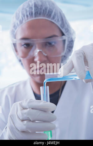 Hispanic scientist pouring liquid into test tube Stock Photo
