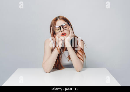 Frustrated Caucasian woman sitting at table Stock Photo