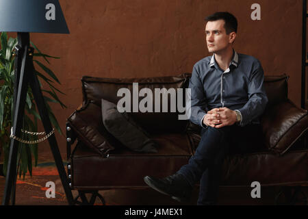 Pensive Middle Eastern man sitting on sofa Stock Photo