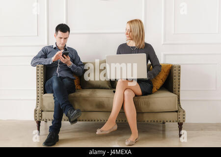 Middle Eastern couple sitting on sofa using technology Stock Photo