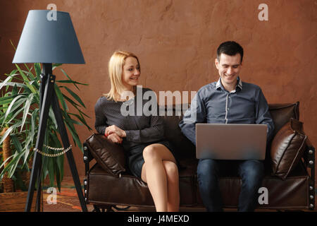 Middle Eastern couple sitting on sofa using laptop Stock Photo