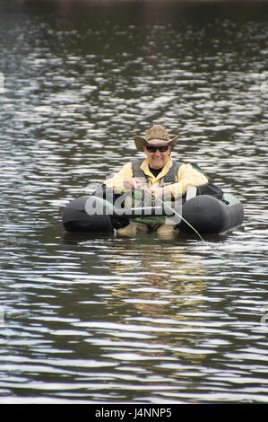 Fishing with a float tube. The man is sitting in the fishing inflatable  boat and he use flippers to move on the water Stock Photo - Alamy