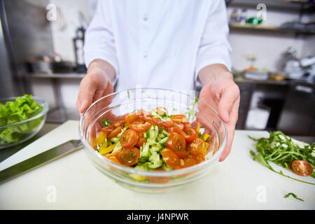 Chef showing cooked salad in bowl Stock Photo