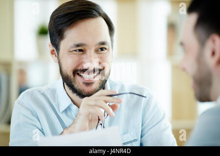 Confident young employer looking at one of applicants during interview Stock Photo