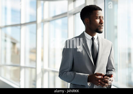 Confident leader with smartphone looking through office window Stock Photo