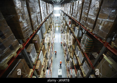 Shelves with goods and workers of warehouse in aisle Stock Photo