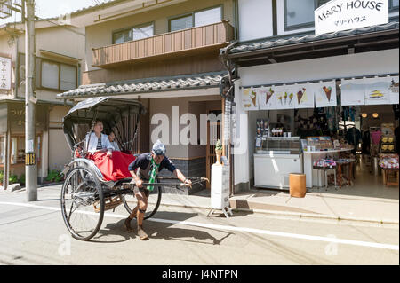 Kyoto, Japan - March 2016: Japanese traditional hand pulled rickshaw carrying tourists on Matsubara street in Kyoto, Japan Stock Photo