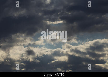 Evening thunderous black clouds in the evening sky, part of the clouds are white, in the blue sky before the rain. Stock Photo