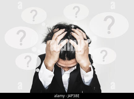 Businessman touching his head, with question marks sign on speech bubbles Stock Photo