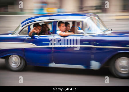 HAVANA - CIRCA JUNE, 2011: Vintage American car serving as shared taxi drives with passengers along the Malecon in Central Havana. Stock Photo