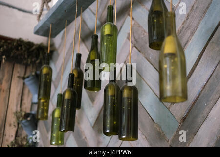 Lamps of green bottles with light bulbs hanging on the background of wooden wall. Horizontal photo Stock Photo