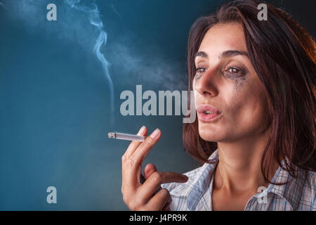 A young woman with a cigarette in his hand on a dark background Stock Photo