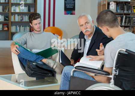 Tutor talking to students, one in wheelchair Stock Photo