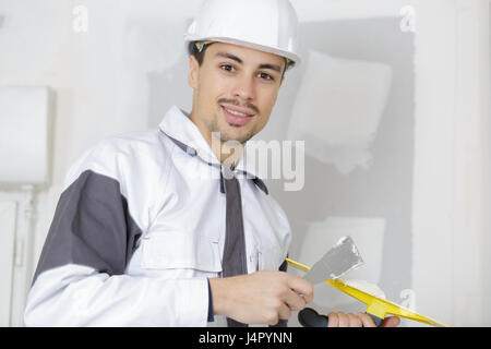 happy builder in hardhat plastering a wall Stock Photo