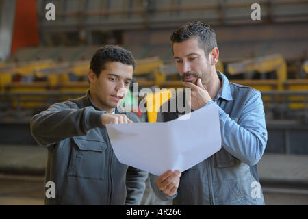 engineers checking installation of new machine in big industrial hall Stock Photo