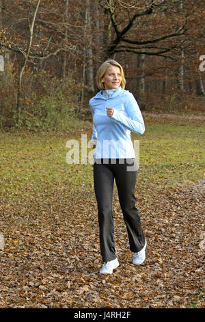 Blond woman, with the jogging in an autumn wood, model released, Stock Photo