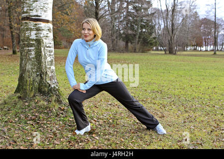 Blond woman, with the jogging in an autumn wood, Stretching, model released, Stock Photo