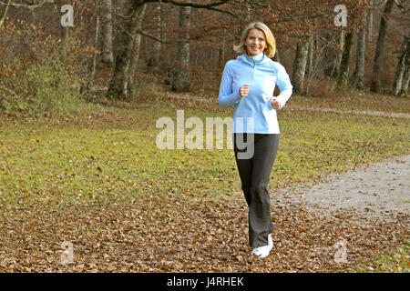 Blond woman, with the jogging in an autumn wood, model released, Stock Photo