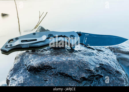 Pocket knife. Knife on wet stone. Folding knife. Stock Photo