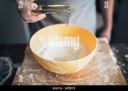 Male baker hands adds ingredients to the bowl. Bread preparation. Homemade bakery. Dough making Stock Photo