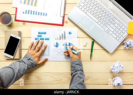 Top view business person discussing charts and graphs  with laptop coffee,smartphone,pen,notebook on office desk. Stock Photo