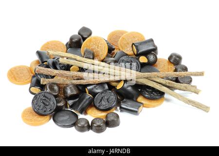 licorice candies with dried sticks of licorice root isolated on white background Stock Photo