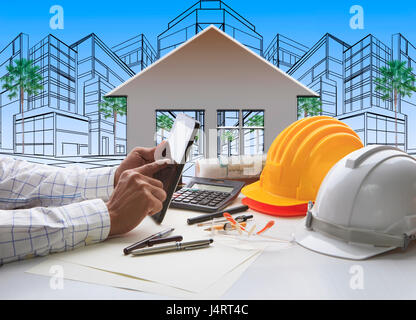 hand of architect working on computer tablet  with construction industry and engineer working tool on top of table against home out line and sketching Stock Photo