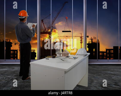 male engineer checking work flow in building construction site against beautiful dusky sky use for construction business and civil engineering Stock Photo