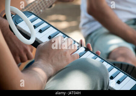 young man plays the Melodica outdoors Stock Photo