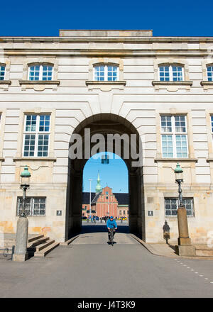 Cyclist riding through archway of Christiansborg Slot, with view of Church of Holmen in background. Copenhagen, Denmark Stock Photo