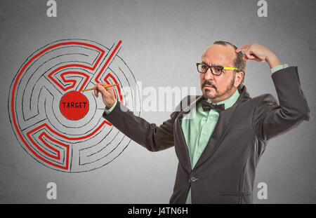 Target man labyrinth. Man drawing with pencil red path line through maze to success isolated grey wall office background. leadership guidance idea ski Stock Photo