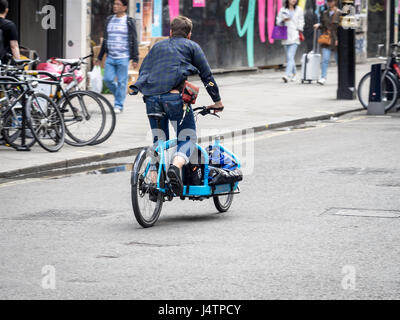 A bike courier delivers goods on a large cargo bike in Central London, UK Stock Photo