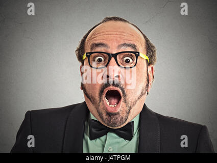 Surprise astonished man. Closeup portrait man looking surprised in full disbelief wide open mouth isolated grey wall background. Positive human emotio Stock Photo
