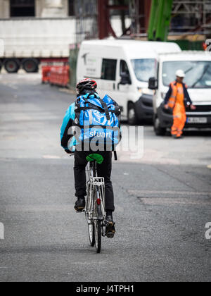 A Stuart company food delivery courier rides through London Streets, Stuart is competing with Deliveroo and Uber Eats in this competitive market Stock Photo