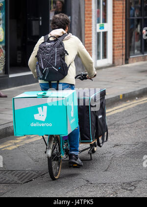 A Deliveroo food delivery cyclist rides a large Cargo Bike in central London. Deliveroo is competing with Uber Eats in the booming food delivery trade Stock Photo