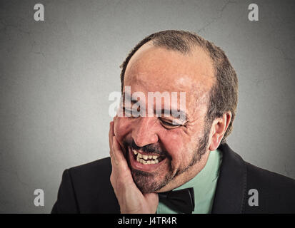 Closeup portrait headshot sad middle aged executive man worker touching face having bad pain suffering from tooth ache isolated grey background. Negat Stock Photo