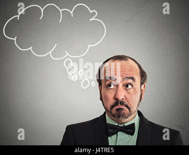 Headshot middle aged man with thoughtful puzzled face expression blank bubble with copy space above head looking up isolated grey wall background. Hum Stock Photo