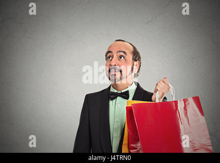 Portrait middle aged gentleman holding shopping bags isolated on grey wall background with copy space. Holiday season concept Stock Photo