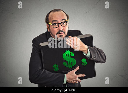 Money greed wealth security. Wealthy business man in suit holding holding hugging tight case full with dollars money isolated grey wall background. Wo Stock Photo